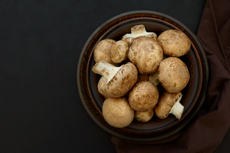 Brown champinon mushrooms (agaricus) in bowl on rustic wooden background. Healthy eating or vegetarian concept. Copy space. Top viewの写真素材