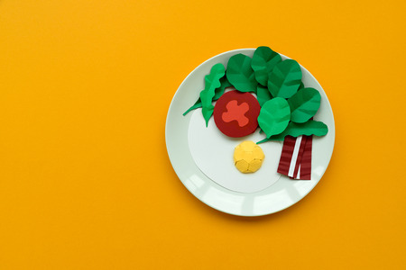 Continental breakfast made from paper: fried egg, tomato, bacon, spinach and arugula on yellow background. Minimal, creative, healthy or food art concept. Copy space. Top viewの写真素材