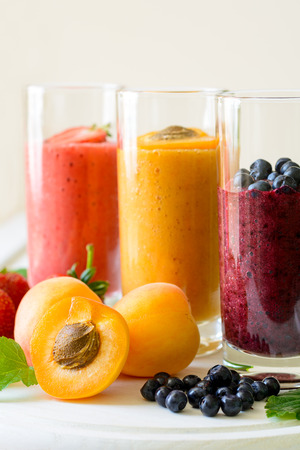 Strawberry, blueberry and apricot smoothies on white wooden background. Detox and healthy eating conceptの写真素材