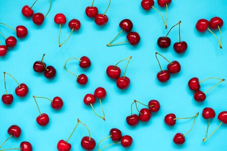 Red ripe cherry beries on blue background. Cherry pattern. Flat lay. Healthy food concept.の写真素材