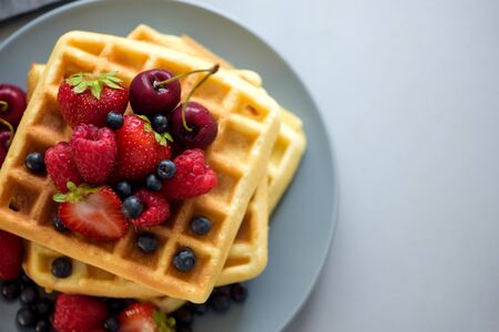 Top view on homemade belgian waffles with berries on gray table. Healthy breakfast concept.の写真素材