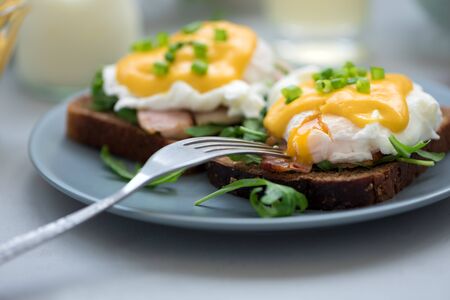 Close up eggs Benedict with arugula, becon and hollandaise sauce on gray wooden background. Soft focus. Healthy eating conceptの写真素材