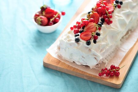 Sponge (biscuit) cake roll filling whipped cream and berries decorated strawberry, blueberry and red...