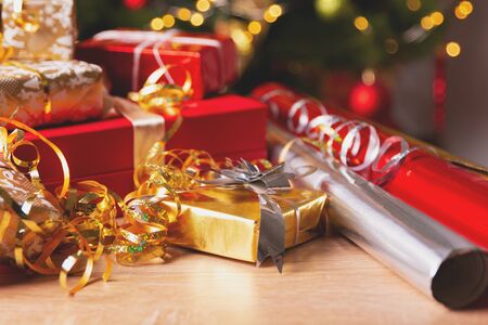 Christmas gift boxes with ribbons and wrapping paper against background bokeh of twinkling party...