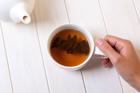 Halloween bat make from tea leaves into tea cup on white wooden table. Halloween celebration concept. Copy spaceの写真素材