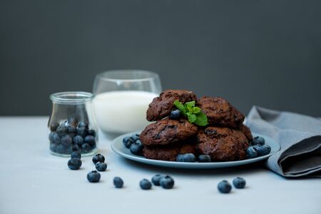Chocolate cookies with chocolate chips and blueberry on gray wooden background. Summer food. Soft focus. Front view. Copy spaceの写真素材