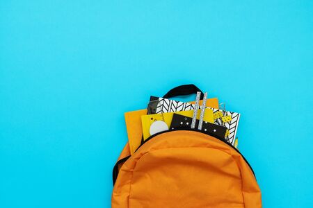 Back to school concept. Backpack with school supplies on blue background. Top view. Copy space. Flat...