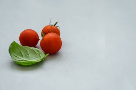 Cherry tomatoes and basil leaves on gray background. Healthy food or cooking concept. Copy spaceの写真素材