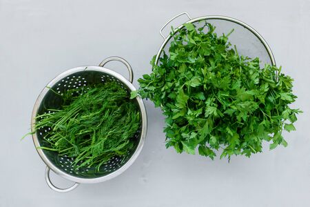 Bowls of fresh green dill or fennel and parsley on gray wooden board. Top view. Copy space. Harvesting conceptの写真素材
