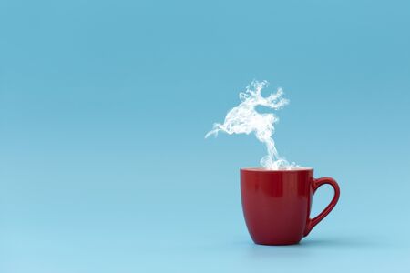 Steam in reindeer shape flying from coffee cup. Morning drink. Christmas or New Year celebration concept. Copy space.の写真素材