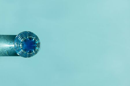 Glass of water with reflecting shadows on blue background.  Healthy food concept. Top view. Copy spaceの写真素材