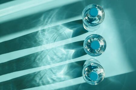 Three bottles of water with reflecting shadows on blue background.  Healthy food concept. Top view. Copy spaceの写真素材