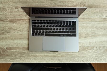 Metallic laptop on wooden table. Top view. Office workplace minimal concept