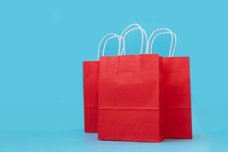 Red paper bags on blue background. Holidays or sale concept. Copy space. Mock-up