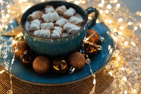 Cup of hot chocolate with marshmallows decorated Christmas baubles and defocused lights on gray wooden background. Christmas and New Year holidaysの写真素材