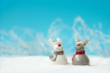 Two ceramic Christmas reindeer toy on snowy background. Christmas or New Year celebration concept. Copy spaceの写真素材