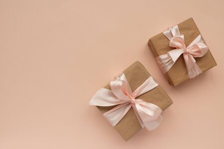 Border from gift boxes wrapped brown craft paper and pink ribbon on red background. Valentines day...
