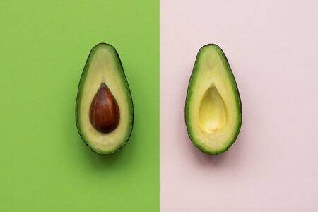 Avocado halves on pink and green background. Top view. Minimal summer food concept. Flat lay