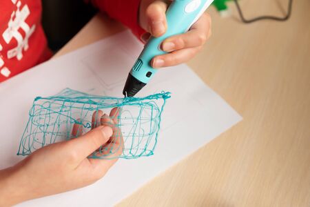 Close-up hands of boy creating volume plastic figure with 3D pen. Selective focus. Education conceptの写真素材