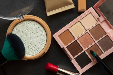 Set of decorative cosmetics, makeup tools and accessories on black slate background. Copy space....