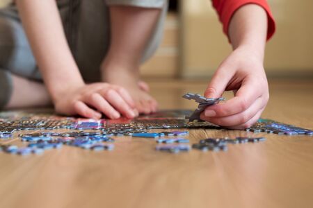 Boy collect puzzle sitting on the floor. Solving difficult tasks or stay at home concept. Soft focus. Zero angleの写真素材