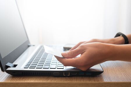 Woman holding credit card and using laptop computer for online shopping.  E-commerce or internet...