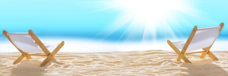Banner 3:1. Deck chairs on sandy beach with blurry blue ocean and sun beams on sky. Social distancing or COVID-19 protection at summer holidays. Summer background. Soft focusの写真素材