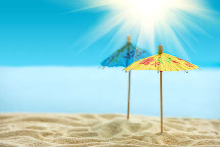 Sun umbrellas on sandy beach with blurry blue ocean, sky and sun beams. Summer background. Soft focusの写真素材