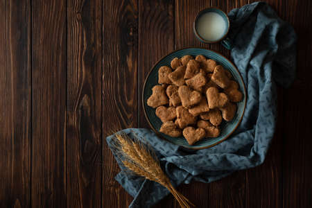 Top view on homemade wholegrain cookies with oatmeal, raisin, nuts, seeds and milk on brown rustic wooden background. Healthy eating concept. Copy spaceの写真素材
