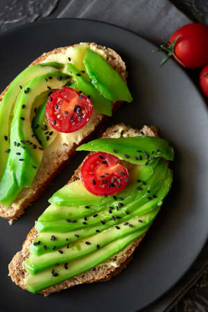 Fresh sandwich on dark rye bread made with fresh sliced avocados, cheese and cherry tomatoes. Top...