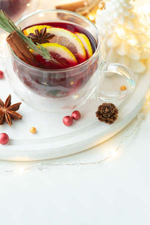 Christmas mulled red wine with spices and citrus on white wooden table. Traditional hot drink at...