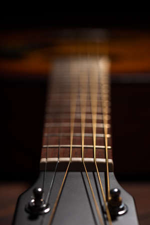Close-up acoustic guitar on wooden background.