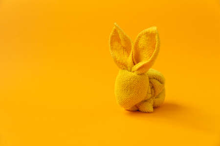 Figure of Easter bunny made of napkin on yellow background. DIY. Easter celebration concept. Soft focusの写真素材