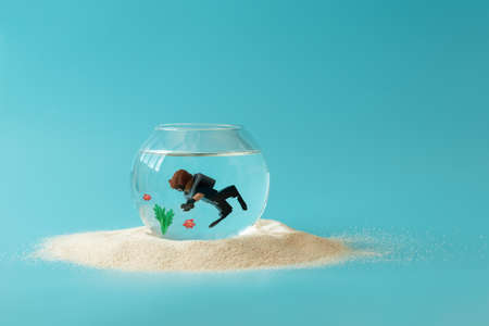 Aquarium with diver toy on blue background. Creative summer vacation conceptの写真素材