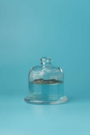 Glass cover dome with tropical island on blue background. Creative summer vacation conceptの写真素材