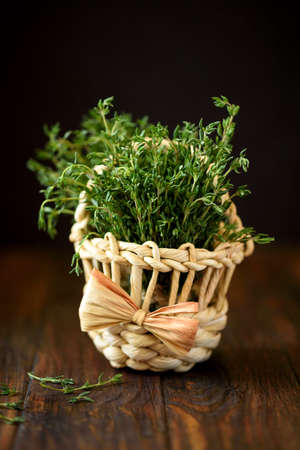 Basket with fresh herb thyme on brown wooden background. Soft focusの写真素材