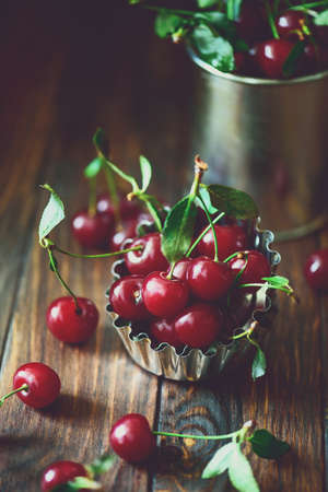 Ripe red cherries in bowl on brown wooden table. Soft focus