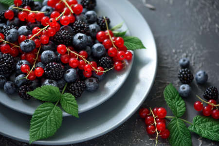 Close-up fresh blueberries, blackberries and red currant on gray concrete background. Selective focusの写真素材