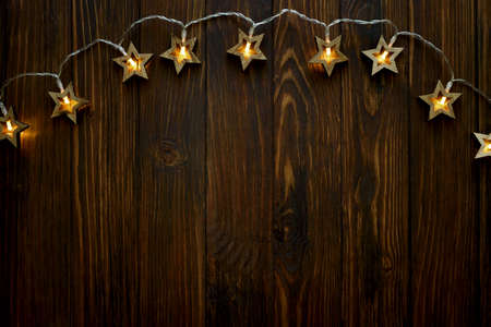 Christmas background with star shape lights on dark wooden board. Top view. Copy space. Xmas decorationの写真素材