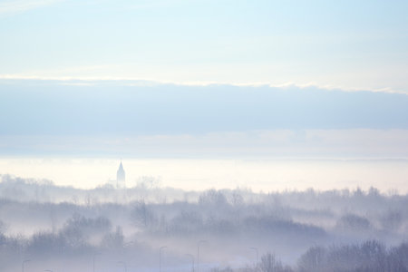 Outlines of trees and church in the fog creeping. Winter landscapeの写真素材