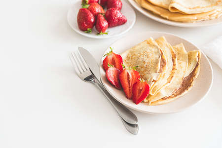 French crepes with chocolate spread and strawberries on white table