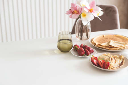 French crepes with chocolate spread and strawberries on white table. Copy spaceの写真素材