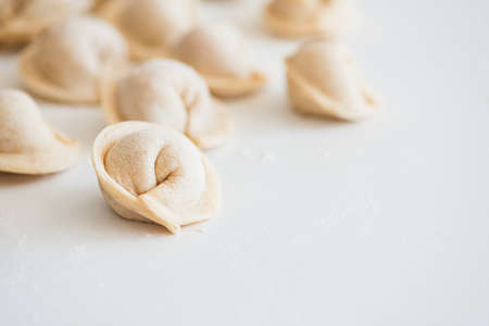 Uncooked homemade pelmeni on white table. Process of making pelmeni, ravioli or dumplings with meat
