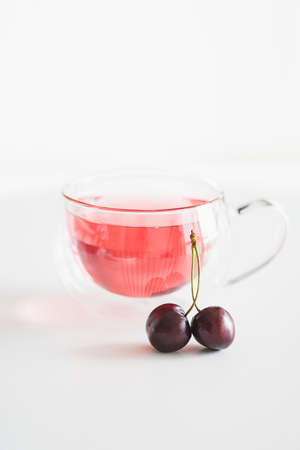 Glass of cherry compote on white wooden tableの写真素材