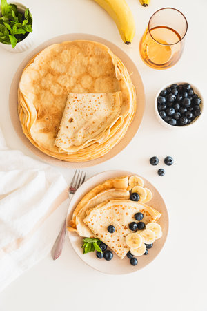 French crepes with banana and blueberries on white table. Top view