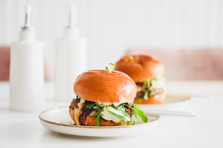 Two delicious homemade burgers with beef, cheese and vegetables on white wooden tableの写真素材