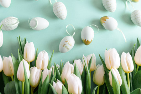 Floral border from bouquet of white tulips, Easter eggs on green background. Easter celebration...