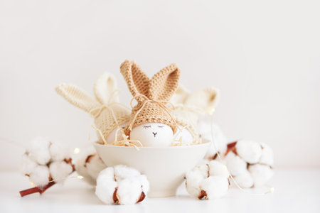 Easter eggs in crochet knitted hats with rabbit ears in nest. Easter celebration concept