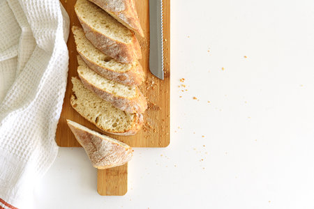 Rustic French sourdough baguette on white wooden table
