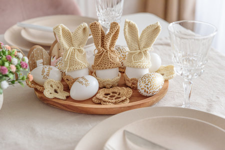 Festive Easter table setting with several Easter bunny made from egg and knitted ears on wooden...